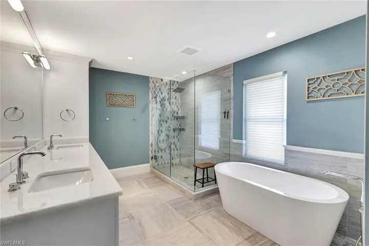 Bathroom featuring vanity, tile walls, and shower with separate bathtub