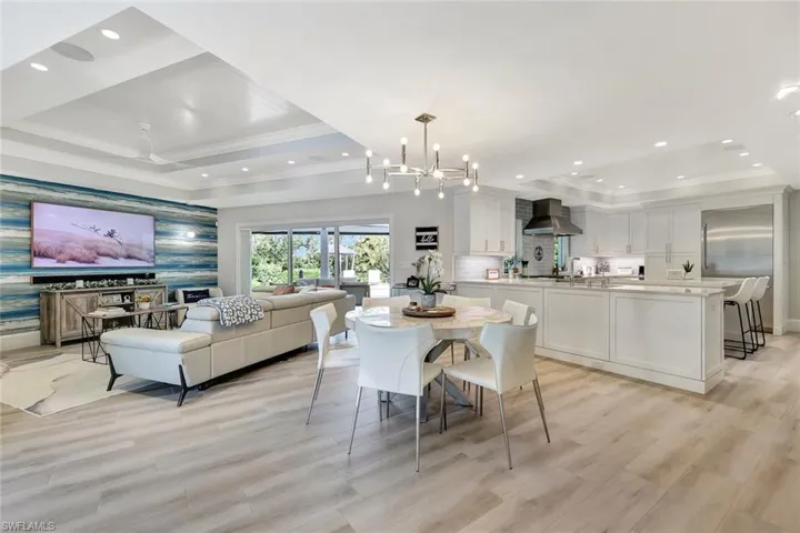 Dining area featuring a raised ceiling, ornamental molding, light hardwood / wood-style flooring, and ceiling fan with notable chandelier