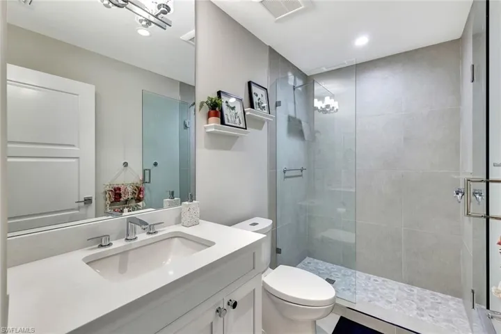 Bathroom featuring vanity, toilet, and a shower with door