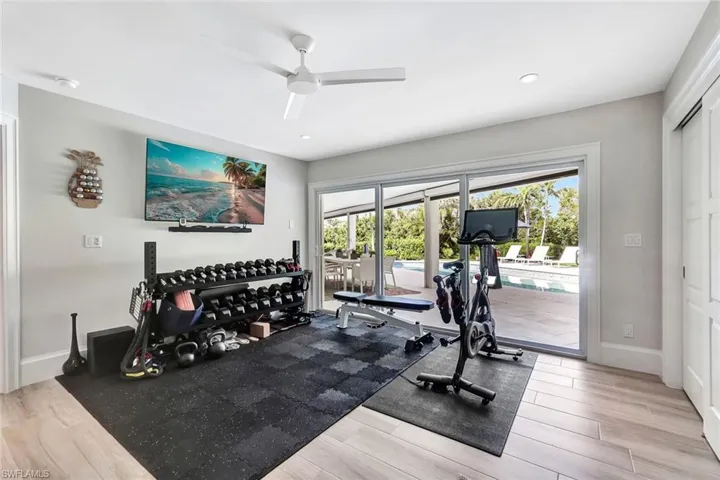Exercise room featuring a pool, light wood-type flooring, and ceiling fan