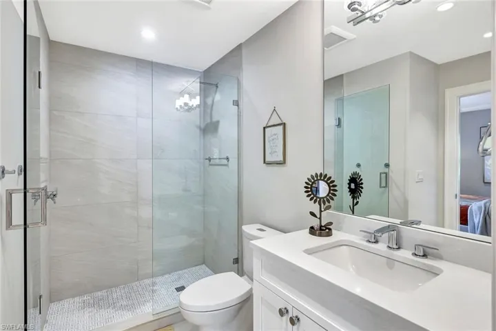 Bathroom featuring toilet, walk in shower, and vanity