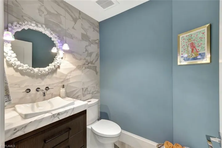 Bathroom featuring vanity, toilet, and tile walls
