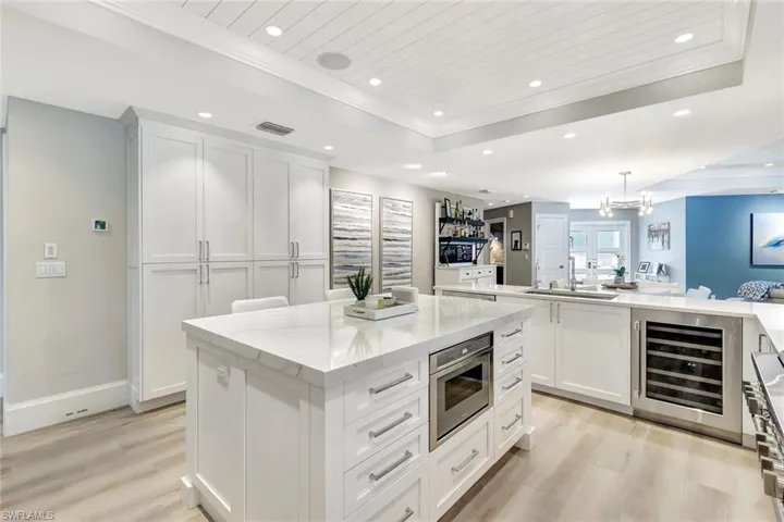 Kitchen featuring a center island, hanging light fixtures, light hardwood / wood-style floors, white cabinets, and wine cooler