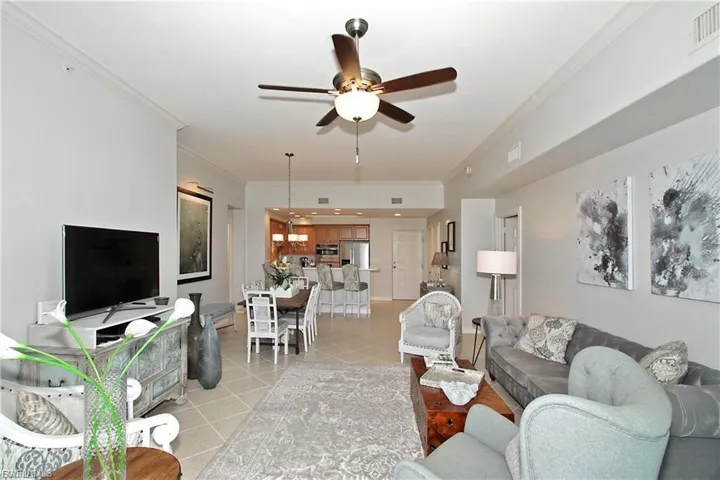 Living room featuring crown molding, ceiling fan, and light tile patterned floors
