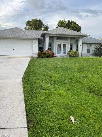 View of front facade with a front lawn, a garage, and french doors
