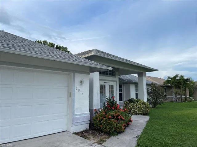 Ranch-style house featuring a garage and a front lawn