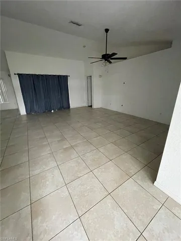 Unfurnished room featuring vaulted ceiling, light tile patterned flooring, and ceiling fan