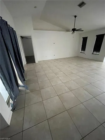 Tiled spare room with ceiling fan and vaulted ceiling