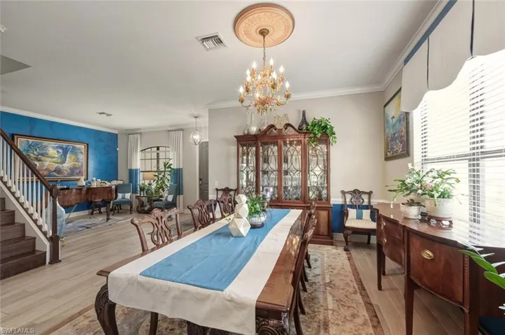 Dining room with ornamental molding, a chandelier, wood finished floors, next to the living room