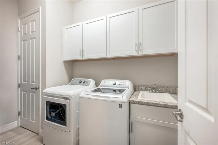 Laundry room featuring cabinet space, washing machine and dryer, and light wood-type flooring