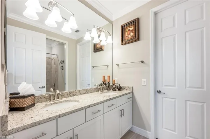 #2 Full bathroom featuring a tile shower, crown molding, and double vanity