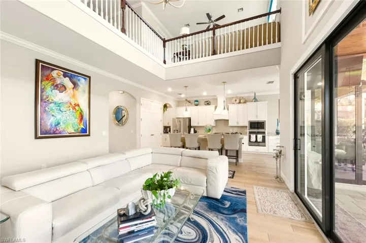 Living room with ornamental molding, a towering ceiling, light wood-style floors, and ceiling fan