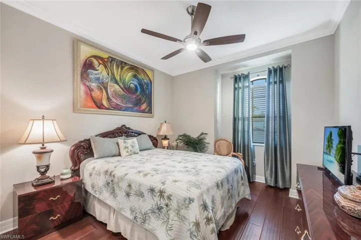 Bedroom with crown molding, dark wood finished floors, and a ceiling fan