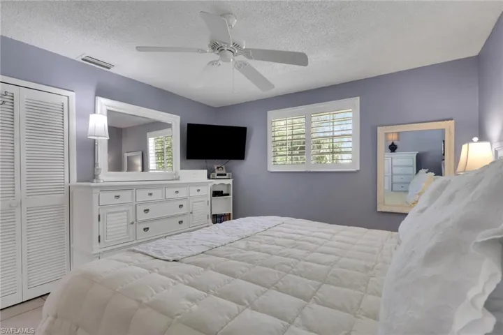 Bedroom with ceiling fan, a closet, and plantation shutters; bed is a king size