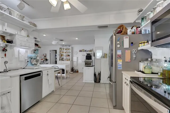 Kitchen featuring open shelves, stainless steel appliances, ceiling fan and white cabinets