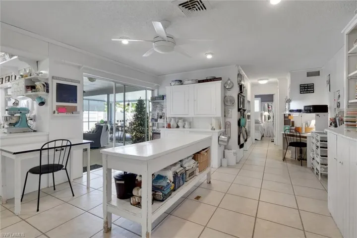 Kitchen featuring white cabinets, light tile patterned floors, a ceiling fan; kitchen work station for prepping or serving and cabinets serve as additional storage space