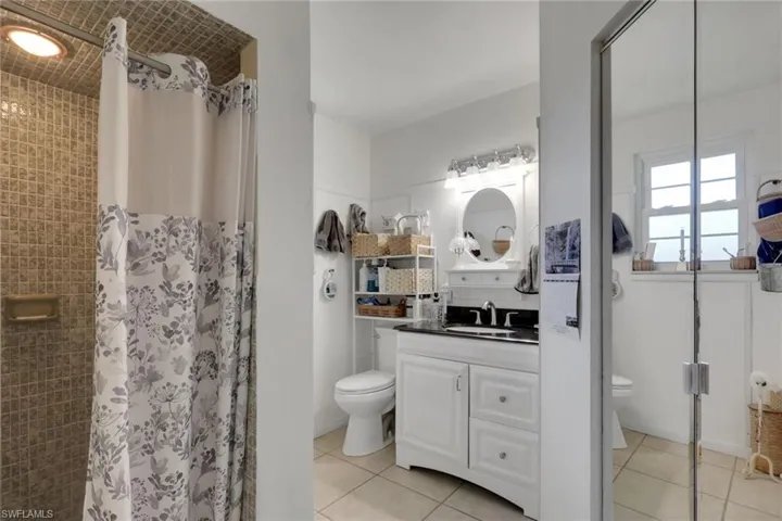 Full bath with a stall shower, vanity, light tile patterned floors, and linen closet