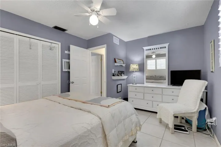 Bedroom featuring plantation shutters, a closet, light tile patterned flooring, and ceiling fan
