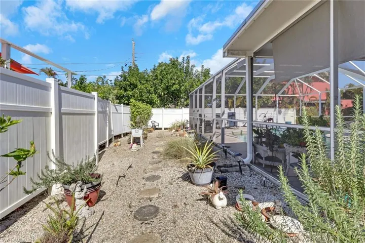 Graveled garden area to the left of the pool cage and property fence