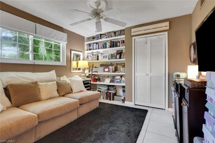 3rd bedroom currently being used as an office/guest bedroom featuring light tile patterned flooring, a ceiling fan, and built in features