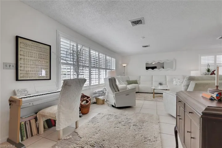 Living area featuring light tile patterned floors and plantation shutters