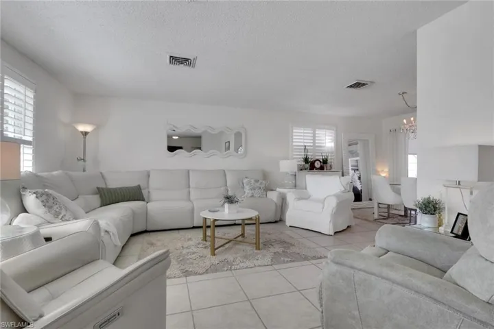 Living room with light tile patterned flooring and plantation shutters
