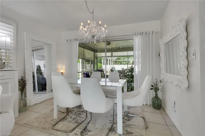 Dining area featuring light tile patterned floors and a chandelier; slider doors open to pool and lanai