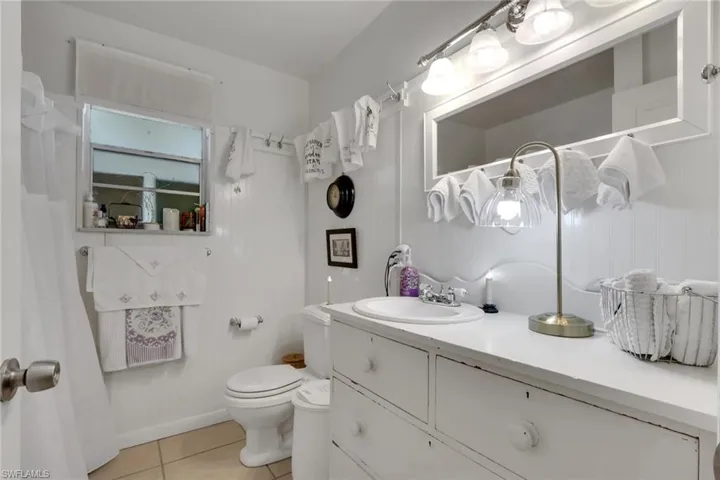 Bathroom with vanity, light tile patterned floors, and a shower/tub combo