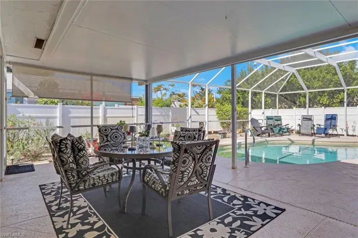 Fenced backyard surrounds back lot; ample dining space and pull down shades; entire area is screened in enclosure