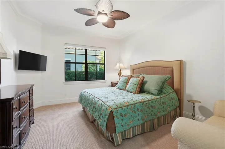 Carpeted bedroom featuring crown molding and ceiling fan