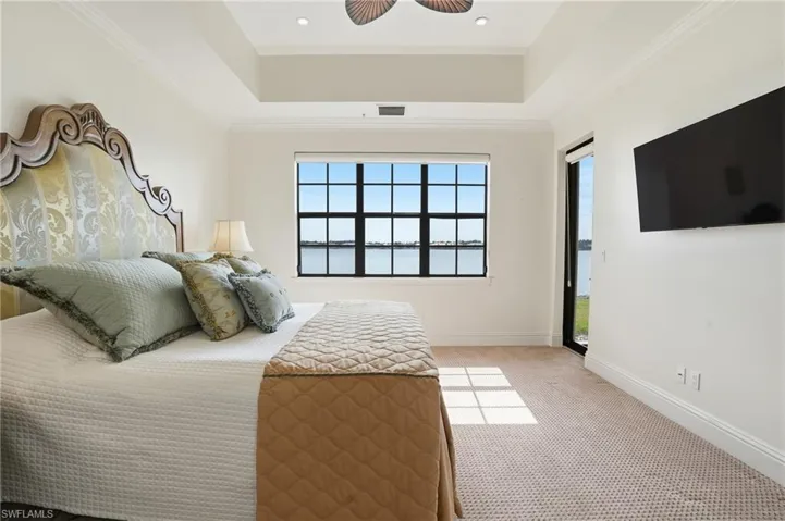 Bedroom with access to outside, light colored carpet, ceiling fan, ornamental molding, and a tray ceiling