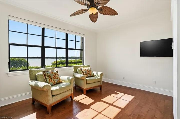 Living area with a water view, hardwood / wood-style floors, crown molding, and ceiling fan