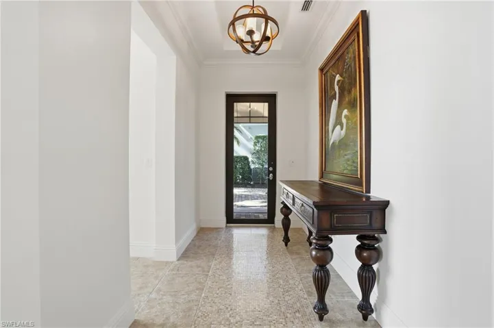 Entryway featuring ornamental molding and a chandelier