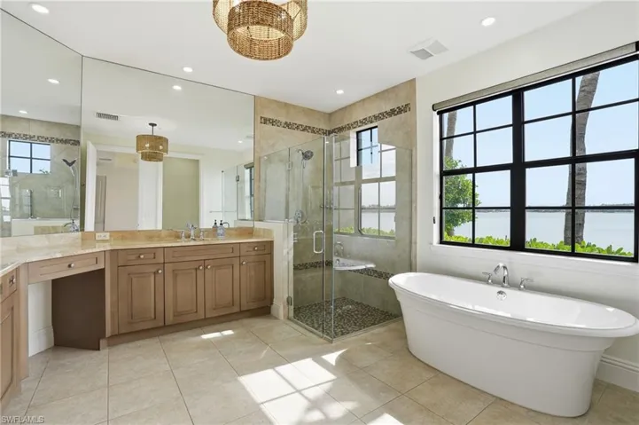 Full bathroom featuring a stall shower, a freestanding tub, vanity, healthy amount of natural light, and recessed lighting