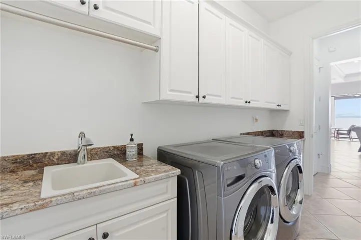 Laundry room with independent washer and dryer, light tile patterned floors, and cabinet space
