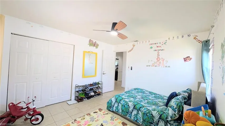Bedroom with ceiling fan, light tile patterned floors, and a closet