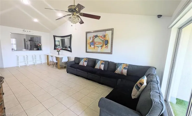 Living area with lofted ceiling, light tile patterned flooring, ceiling fan, and recessed lighting