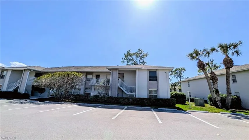 View of property featuring stairway and uncovered parking