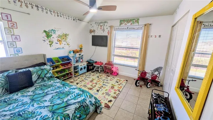 Bedroom with a ceiling fan, light tile patterned floors, and a closet