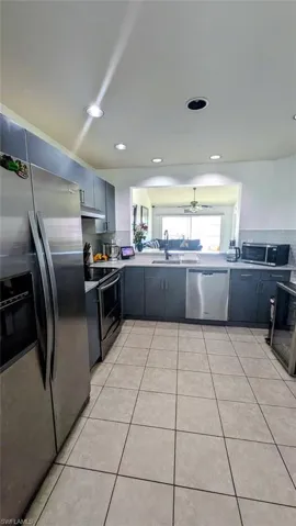 Kitchen with stainless steel appliances, tasteful backsplash, gray cabinets, light countertops, and light tile patterned flooring