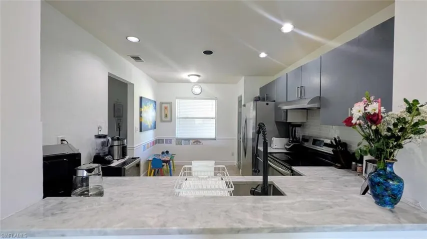 Kitchen with electric range, backsplash, a peninsula, and recessed lighting