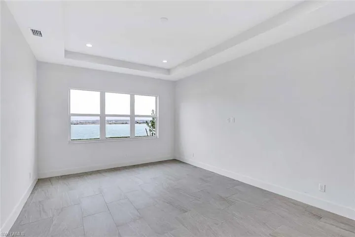 Primary bedroom suite back of house with gorgeous water view and elegant tray ceiling addition