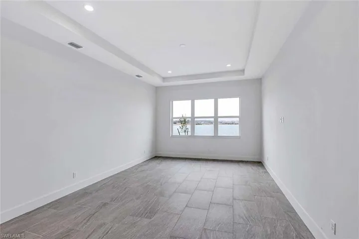 Primary bedroom suite back of house with gorgeous water view and elegant tray ceiling addition