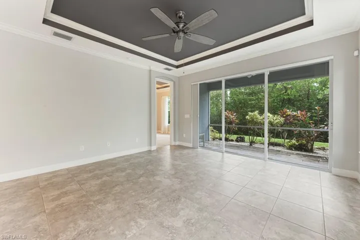 Living room with a tray ceiling, ornamental molding, and ceiling fan