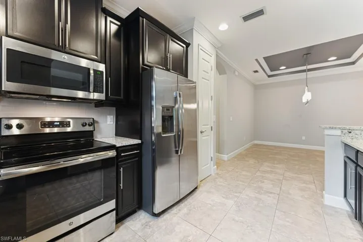 Kitchen featuring ornamental molding, light stone counters, stainless steel appliances, and backsplash