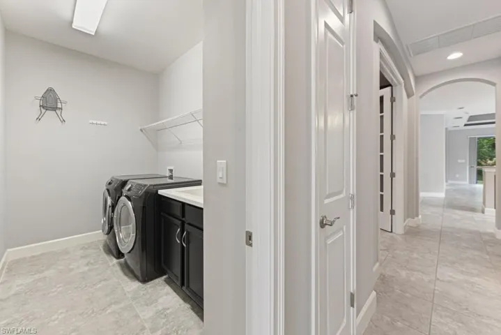 Laundry room with cabinets, independent washer and dryer, and light tile patterned flooring