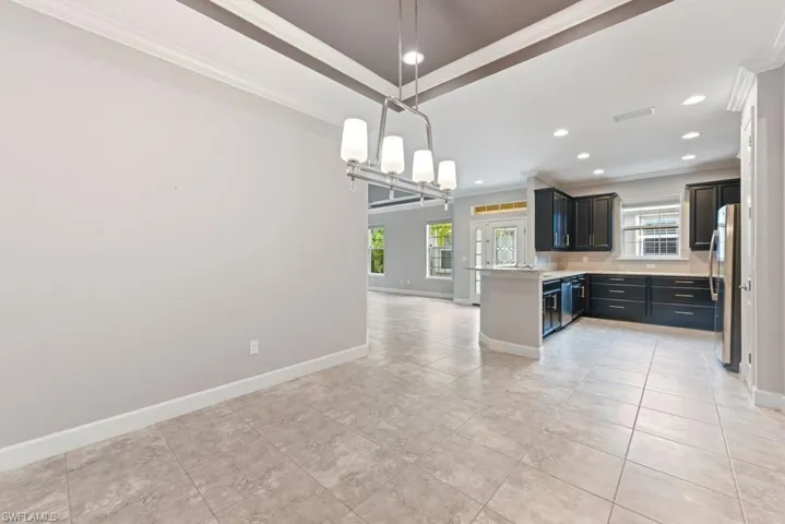 Kitchen with stainless steel fridge, ornamental molding, kitchen peninsula, and a healthy amount of sunlight