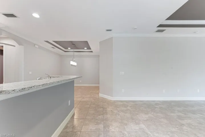 Empty room featuring light tile patterned floors, a raised ceiling, crown molding, and sink