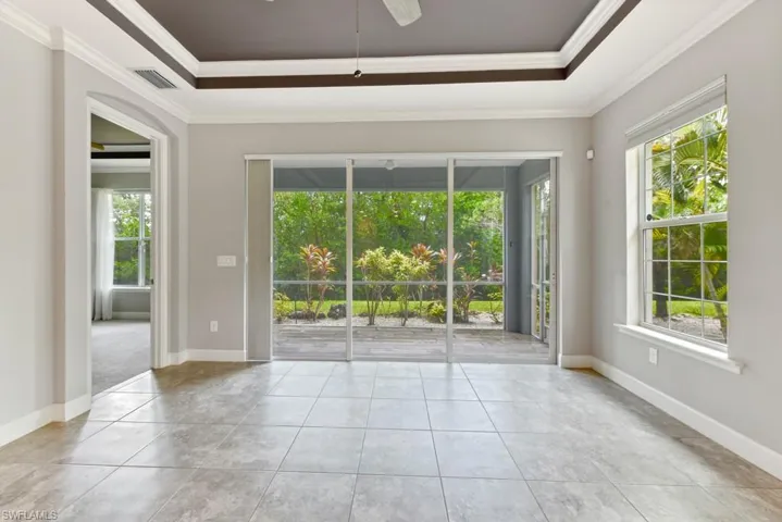Tiled empty room with crown molding, plenty of natural light, and ceiling fan