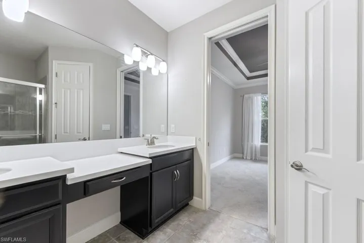 Bathroom with crown molding, vanity, a shower with shower door, and tile patterned floors